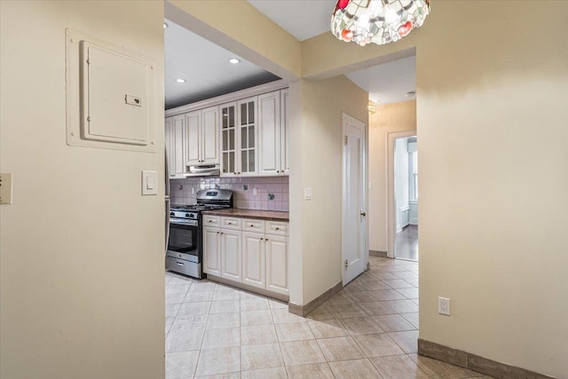 kitchen featuring electric panel, tasteful backsplash, gas stove, glass insert cabinets, and white cabinetry