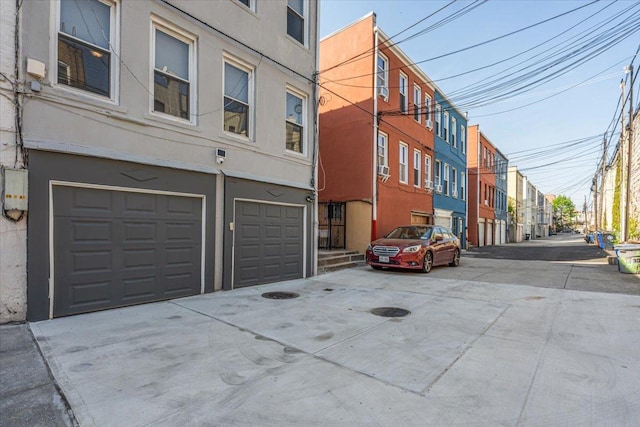view of building exterior featuring an attached garage, driveway, and a residential view