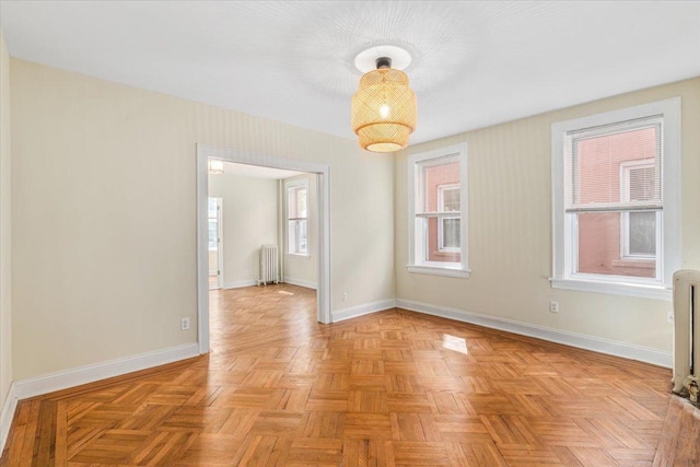 spare room with radiator, baseboards, and a wealth of natural light