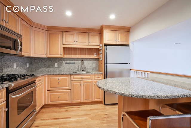 211 Thompson St Unit 5L, New York City, NY 10012 - kitchen featuring stainless steel appliances, light brown cabinetry, light wood-type flooring, backsplash, and light stone counters