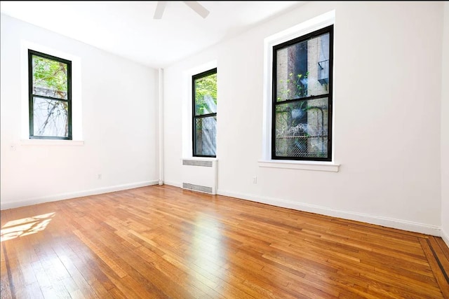 250 W 22nd St Unit 1-B, New York City, NY 10011 - empty room featuring radiator, light wood-style flooring, a ceiling fan, and baseboards