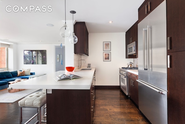 kitchen with a sink, high end appliances, dark brown cabinets, and light countertops