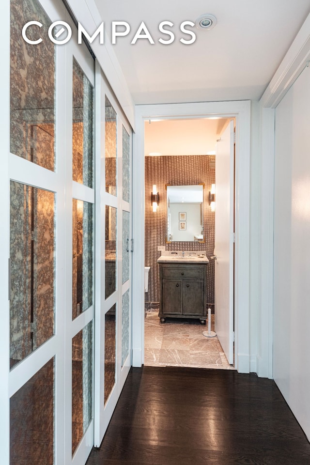 corridor with french doors, a sink, and wood finished floors