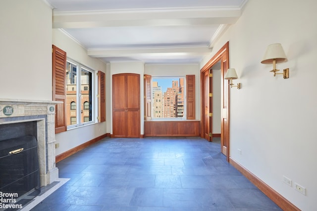 unfurnished living room with crown molding, baseboards, stone finish flooring, and a fireplace