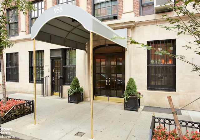 property entrance with brick siding, stucco siding, and french doors