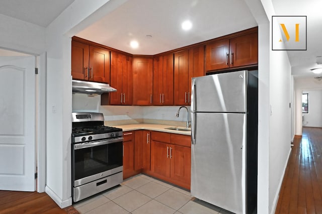 kitchen featuring recessed lighting, light countertops, under cabinet range hood, a sink, and appliances with stainless steel finishes
