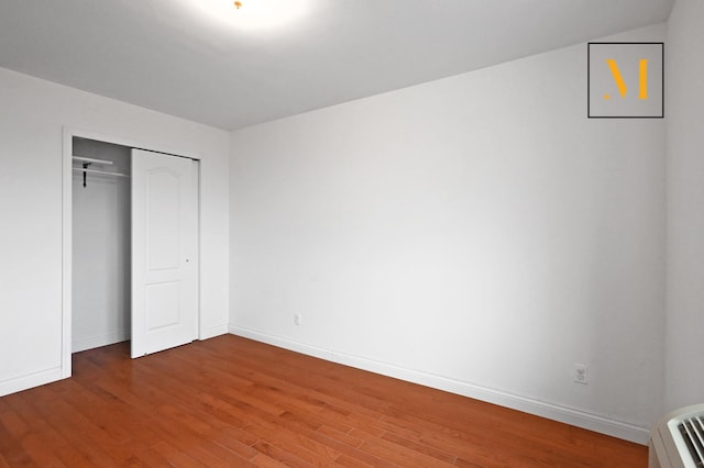 unfurnished bedroom featuring baseboards, a closet, and wood finished floors