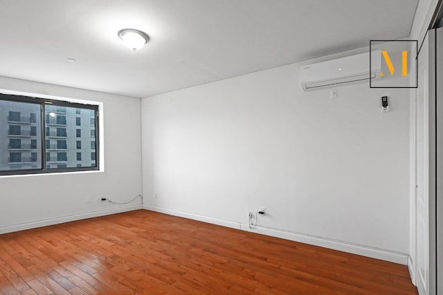 unfurnished room featuring baseboards, an AC wall unit, and wood finished floors