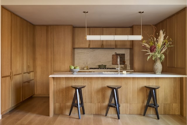 interior space featuring light wood-type flooring, light countertops, a sink, and a kitchen breakfast bar