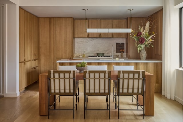 bar featuring decorative backsplash, a sink, and light wood-style floors