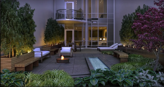 view of patio with an outdoor fire pit and a balcony