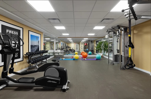 gym featuring baseboards, a paneled ceiling, and visible vents