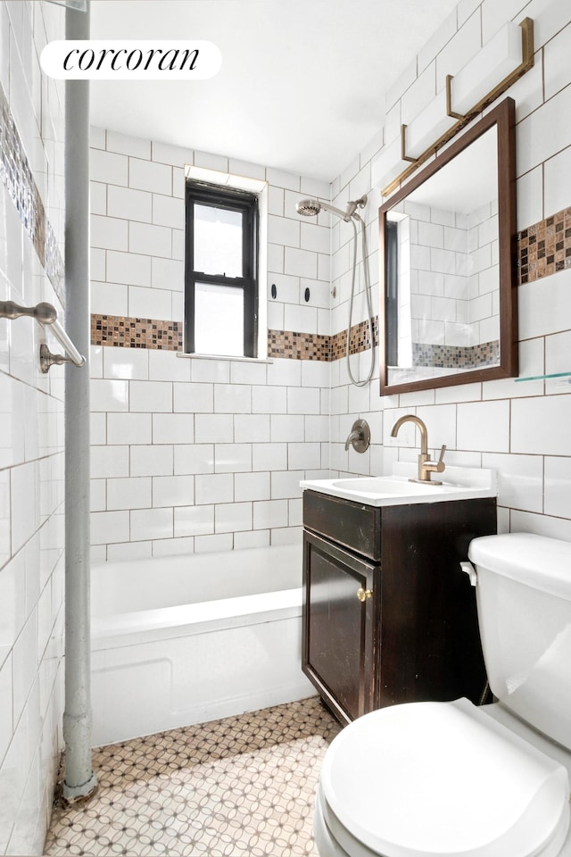 bathroom featuring tile walls, toilet, washtub / shower combination, and vanity