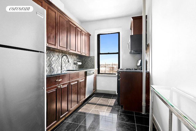 kitchen featuring stainless steel appliances, a sink, decorative backsplash, and baseboards