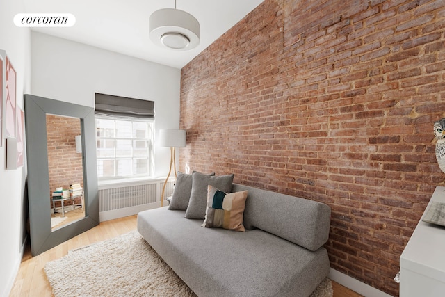 sitting room with brick wall, wood finished floors, and visible vents