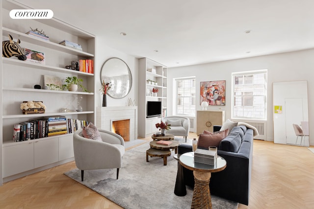living room featuring built in features and a lit fireplace
