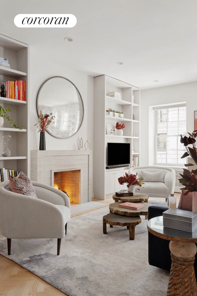 living area featuring built in features and a lit fireplace
