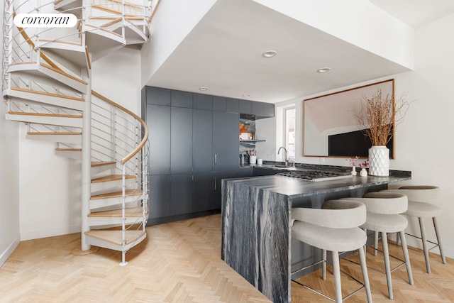 kitchen with a kitchen breakfast bar, dark countertops, a sink, baseboards, and recessed lighting