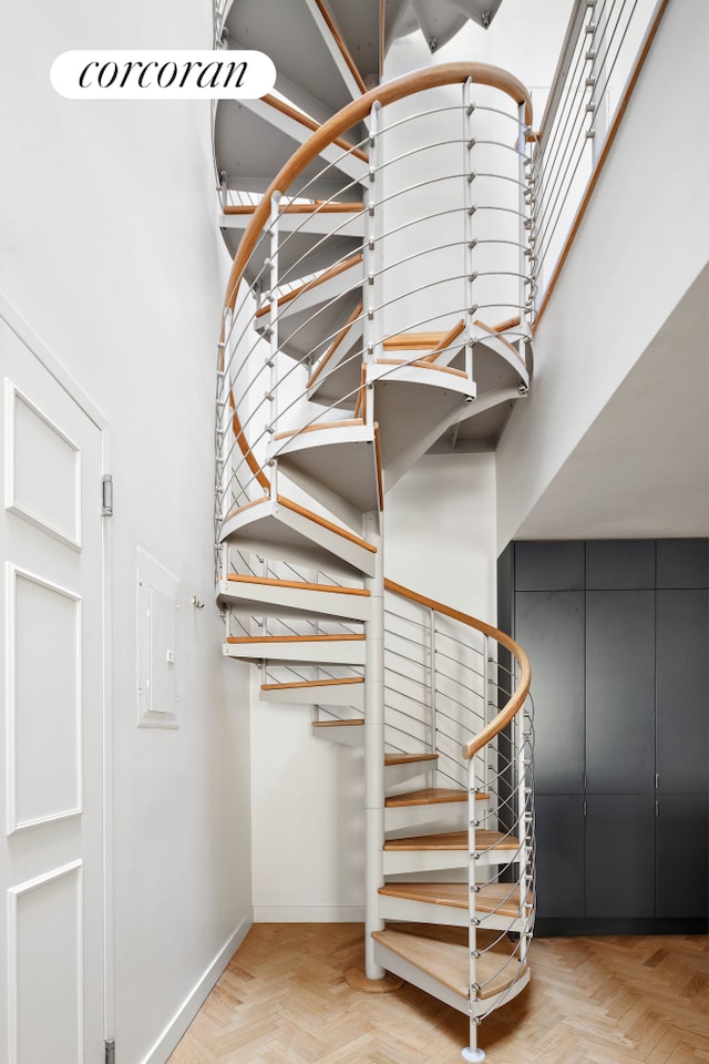 staircase featuring baseboards and a high ceiling