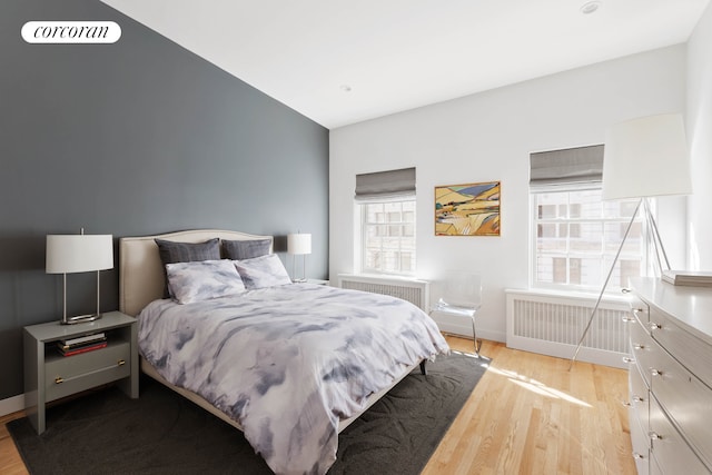 bedroom featuring baseboards, radiator, and wood finished floors