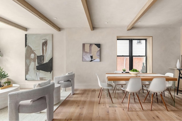 dining space featuring baseboards, hardwood / wood-style flooring, and beam ceiling