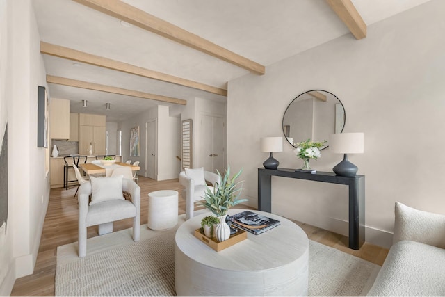 dining space with baseboards, beam ceiling, and light wood-style floors