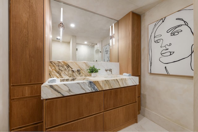 bathroom with vanity, baseboards, and a shower
