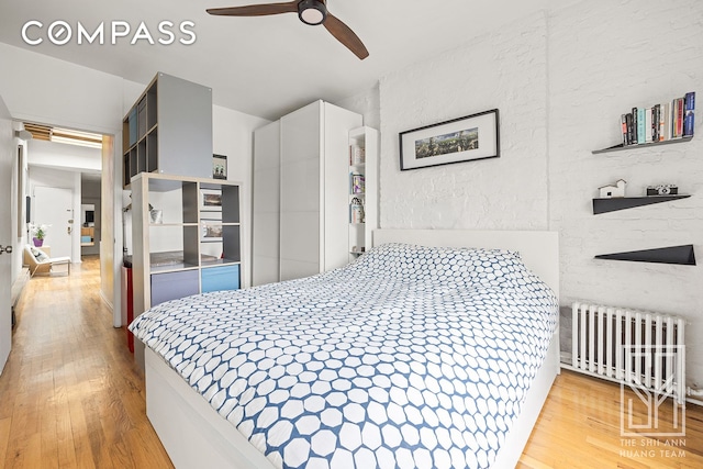 bedroom featuring a ceiling fan, wood finished floors, and radiator