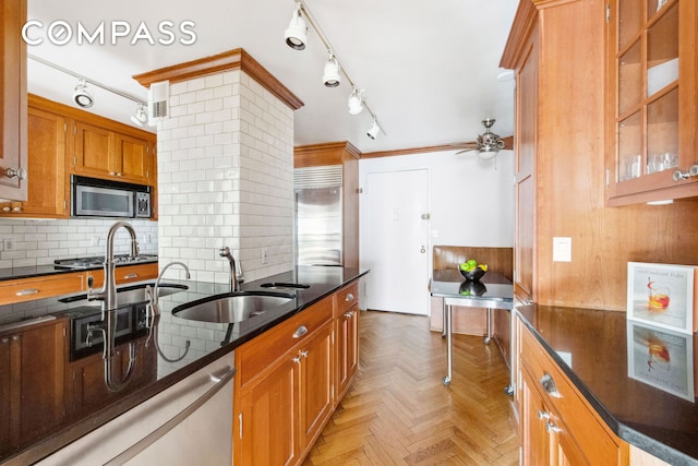 kitchen with decorative backsplash, ceiling fan, brown cabinets, a sink, and appliances with stainless steel finishes