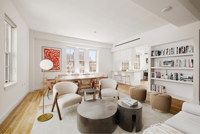 sitting room with light wood-type flooring, baseboards, and built in shelves