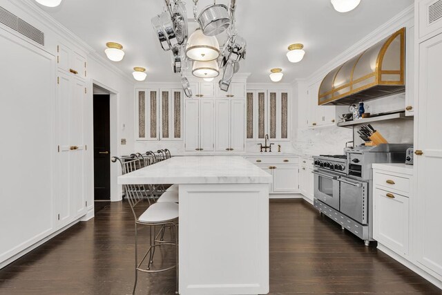1133 Park Ave Unit 2W, New York City, NY 10128 - kitchen with visible vents, high end stainless steel range, dark wood-style floors, a kitchen bar, and custom range hood