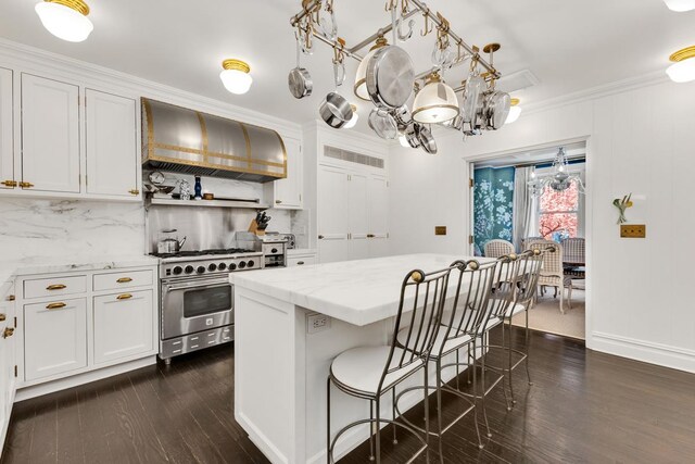 1133 Park Ave Unit 2W, New York City, NY 10128 - kitchen with decorative backsplash, dark wood-style flooring, high end range, white cabinets, and wall chimney exhaust hood