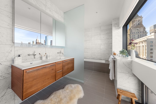 123 3rd Ave Unit Ph18, New York City, NY 10003 - bathroom featuring tile walls, double vanity, a bath, a view of skyline, and tile patterned floors