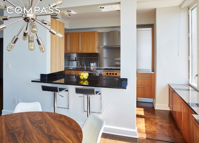 220 Riverside Blvd Unit 19Jg, New York City, NY 10069 - kitchen with a chandelier, brown cabinetry, a kitchen bar, backsplash, and baseboards