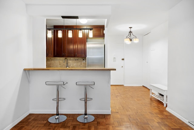 210 E 15th St Unit 4J, New York City, NY 10003 - kitchen with built in fridge, decorative backsplash, baseboards, and hanging light fixtures