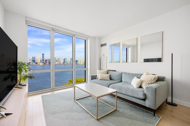 living room featuring a water view, a city view, visible vents, and wood finished floors
