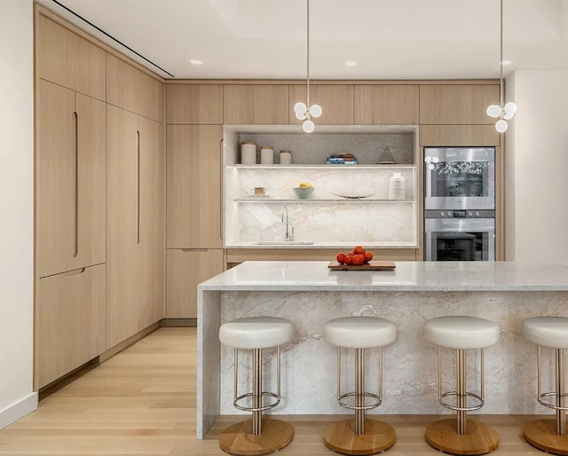 20 River Ter Unit 11L, New York City, NY 10282 - kitchen with a sink, a kitchen bar, light wood finished floors, and light stone counters