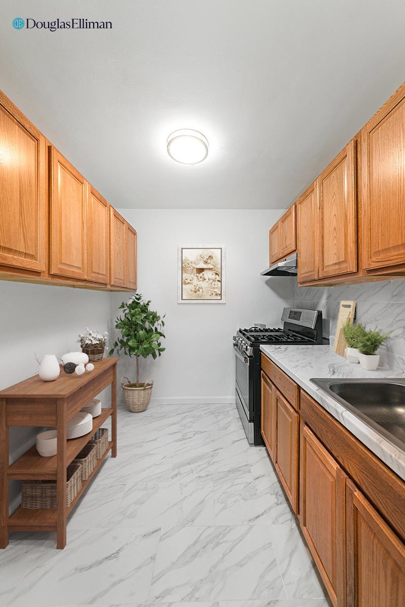 310 Lenox Rd Unit 4U, New York City, NY 11226 - kitchen featuring stainless steel gas range oven, under cabinet range hood, light marble finish floors, light countertops, and baseboards