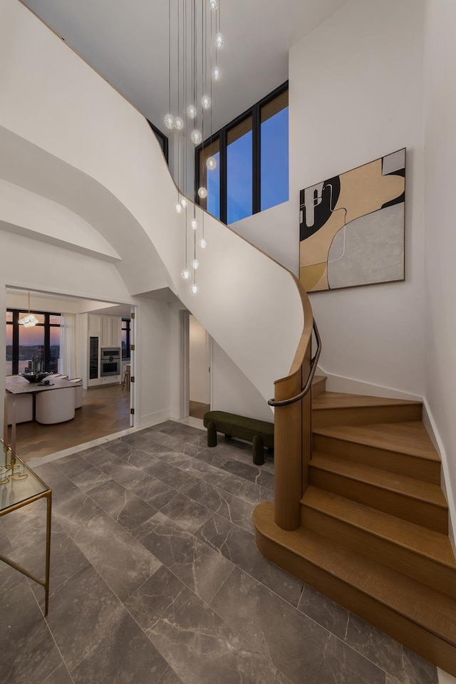stairs featuring marble finish floor, baseboards, and high vaulted ceiling