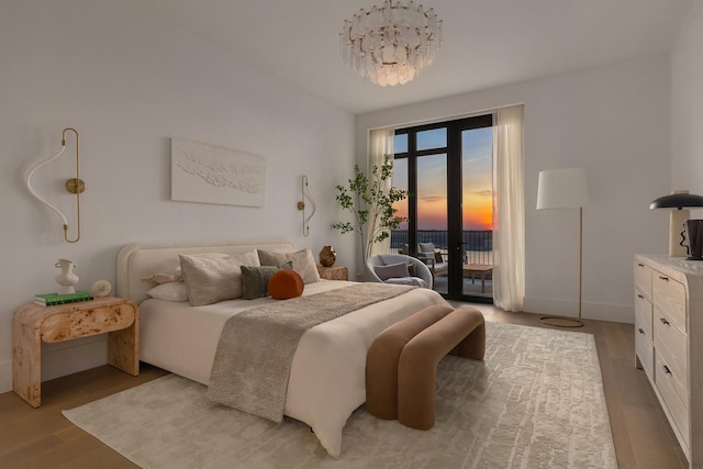 bedroom with baseboards, a chandelier, access to exterior, and light wood-style flooring