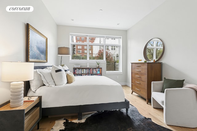 bedroom with multiple windows, light wood finished floors, and baseboards