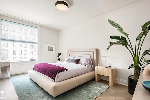 bedroom with baseboards, ornamental molding, and wood finished floors