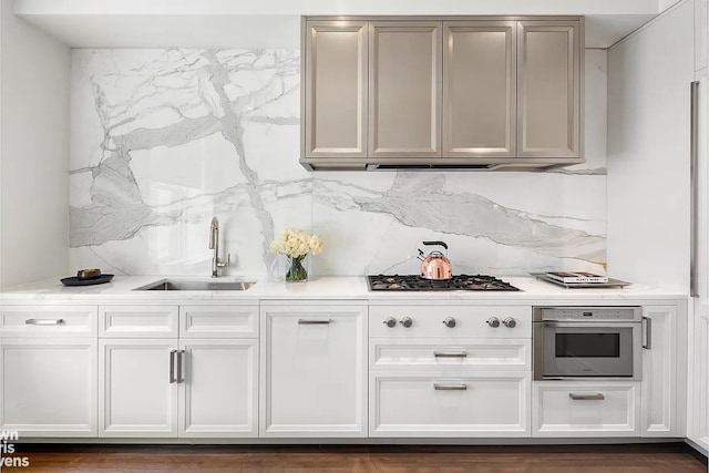 bar with oven, gas cooktop, decorative backsplash, and a sink