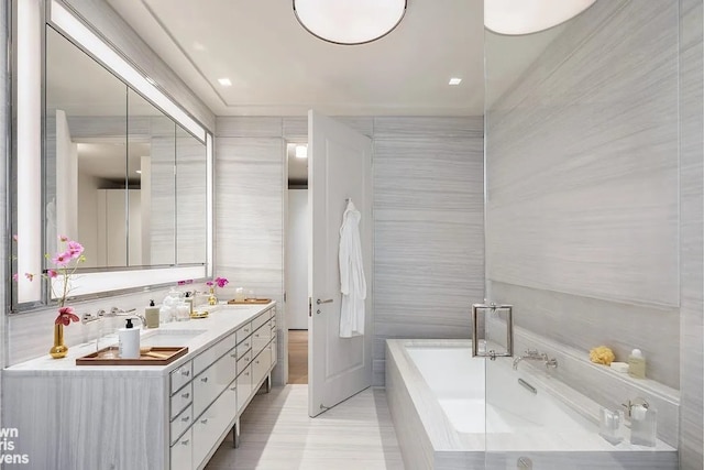 full bathroom with double vanity, tile walls, and a bath
