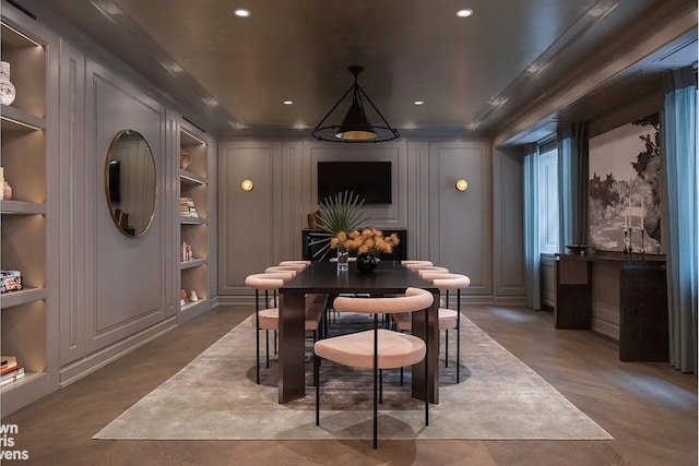 dining space featuring concrete floors, built in features, ornamental molding, and a decorative wall