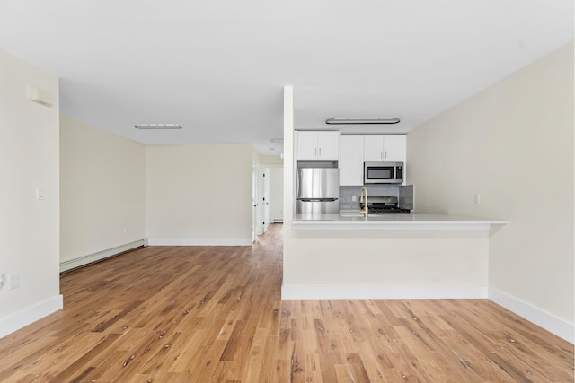 2108 Dean St, New York City, NY 11233 - kitchen featuring a baseboard radiator, appliances with stainless steel finishes, light wood finished floors, backsplash, and white cabinetry