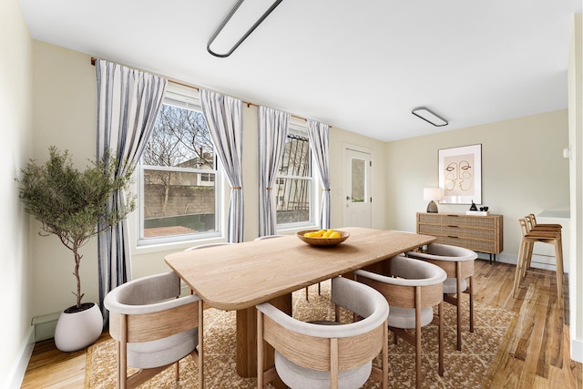dining space featuring baseboards and light wood finished floors