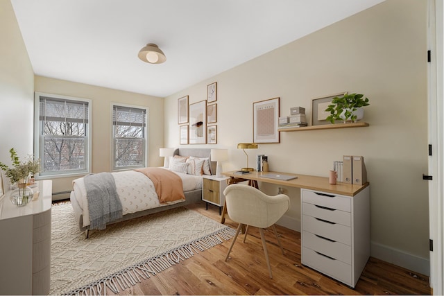 bedroom featuring baseboards, a baseboard radiator, and wood finished floors