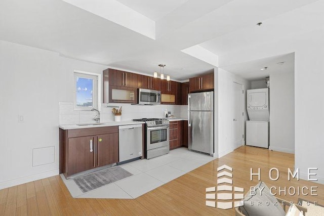 302 2nd St Unit 12H, New York City, NY 11215 - kitchen featuring stainless steel appliances, stacked washer / dryer, a sink, light countertops, and light wood-type flooring
