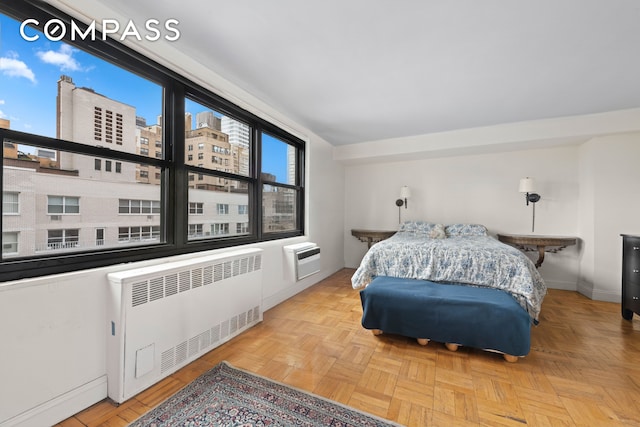 bedroom with radiator heating unit, baseboards, and an AC wall unit